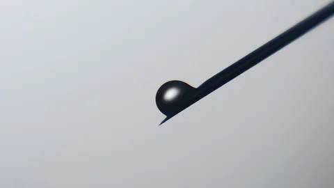 Black fluid drops grow big on a metallic needle and fall in a scientific lab Stock-Footage 87646616