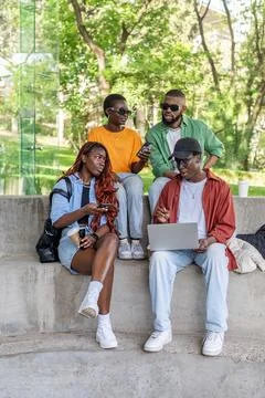 Black focused student friends work on laptop at park bench, chat in social media Stock Photos