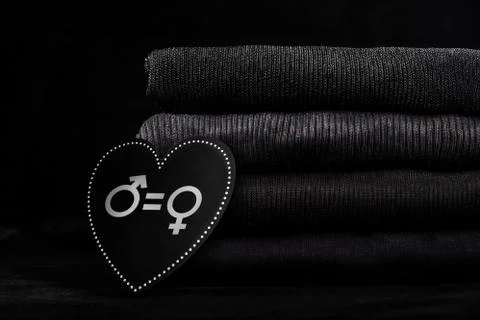 Black folded clothes in a pile and a wooden board in the shape of a heart with Stock Photos