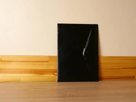 Black folder standing on wooden surface near light wall, minimalist office co Stock Photos