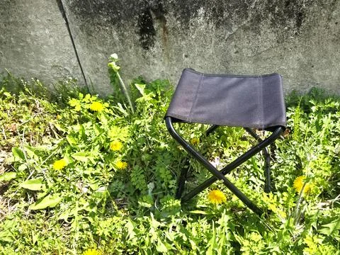 Black folding stool placed on green grass, capturing a simple yet functional out Foto stock