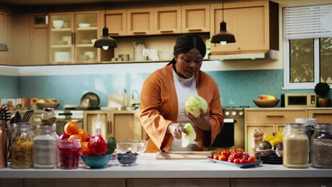 Black food content creator preparing iceberg salad leaves on cooking video Stock Footage 333609199