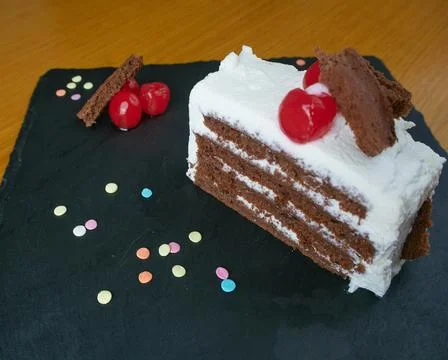 Black forest slice decorated with cherries, small pieces of cake and decorati Stock Photos