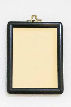 Black frame with a beige background inside on a textured white wall. Mockup.. Stock Photos