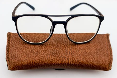 Black frame spectacles kept on a brown leather case Stock Photos