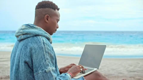 Black freelancer work outdoor ocean beach. African american person use laptop. Stock Footage 246407204