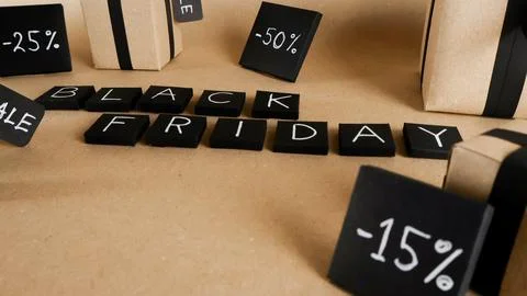 Black Friday lettering surrounding gift boxes and discount signs Stock Photos