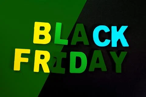 Black friday text in colorful letters on black and green background. Stock Photos