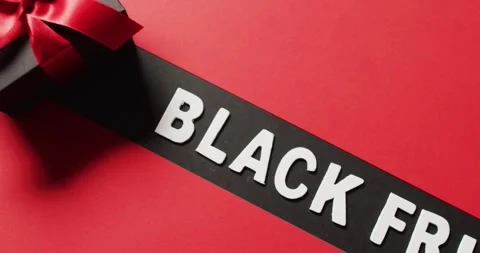 Black friday text in white on black stripe and black gift box with red ribbon, 動画素材 336783596