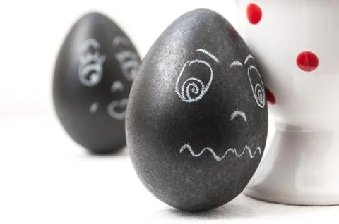Black funny easter eggs with expressive face drawn in chalk Stock Photos