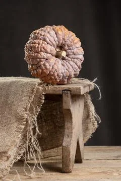 Black Futsu Mini Pumpkin On Rustic Wooden Stool Stock Photos