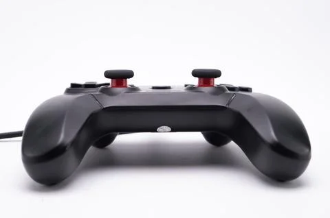 Black Game Controller with Red Joysticks on White Background, Close-up View. Stock Photos