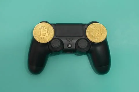 Black gaming controller with Bitcoin Tokens isolated on green background. Stock Photos