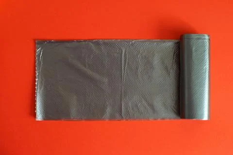 Black garbage bag on a red background. Stock Photos