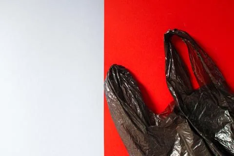 Black garbage bag roll on red background. Stock Photos