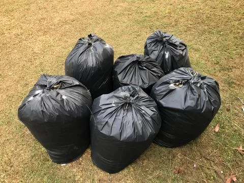 Black garbage bags in the yard. Selective focus. Stock Photos