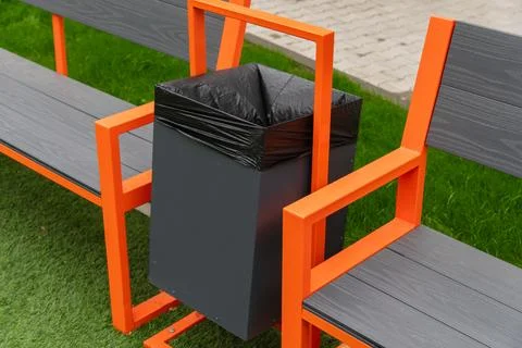 A black garbage can with a black plastic liner is mounted to an orange Stock Photos