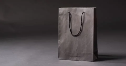 Black gift bag with black handles on dark grey background with copy space Vidéo 336304814