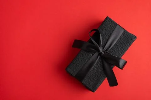 Black gift box creating elegant surprise on red background Stock Photos