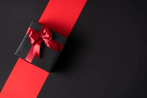 Black gift box on a dark contrasting background, decorated with a bright text Stock Photos