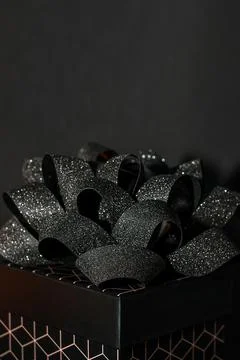 A black gift box with a geometric pattern and a black bow on a black backgrou Stock Photos