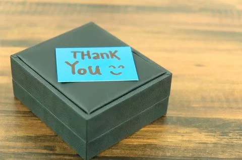 A black gift box with a note that said "Thank you" on it. Stock Photos