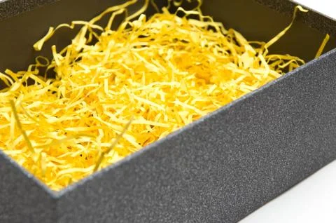 Black gift box with yellow packaging material Stock Photos