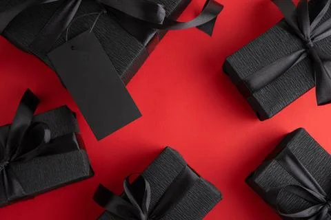 Black gift boxes with blank tag on red background Stock Photos