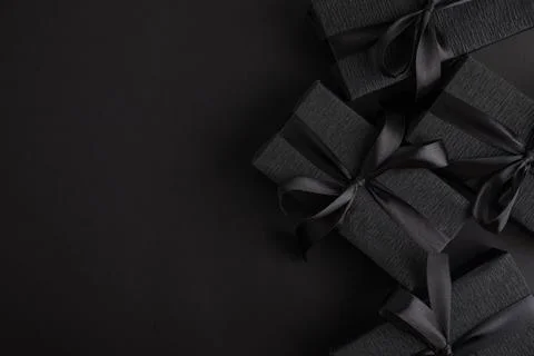 Black gift boxes with ribbon on dark background Stock Photos