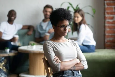 Black girl outcast sitting apart from peers in cafeteria Stock Photos
