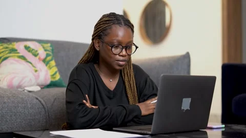 A black girl taking notes while looking at a laptop screen Stock Footage 265886658