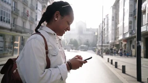 Black girl using cell phone on street. Side view happy woman traveler backpack Stock Footage 249393985