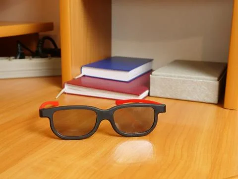 Black glasses with red temples lying on wooden desk, notebooks and box in the Stock Photos