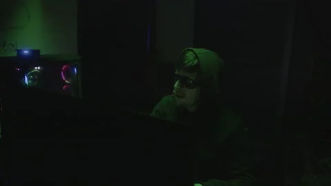 Black Glasses-Wearing Hacker Hacking at Computer, Green Light ambiance Stock Footage 234143618
