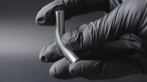 A black glove on the hands , a spring is shown in the hands and how it bends in  Stock Footage 304536571