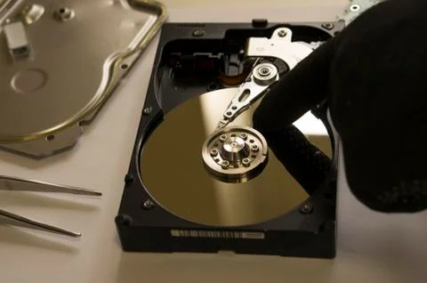 A black gloved hand of a foreman indicates damage to the computer's hard drive Stock Photos