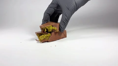 A black-gloved hand places a slice of Dubai chocolate on top of another slice Stock Footage 293644533