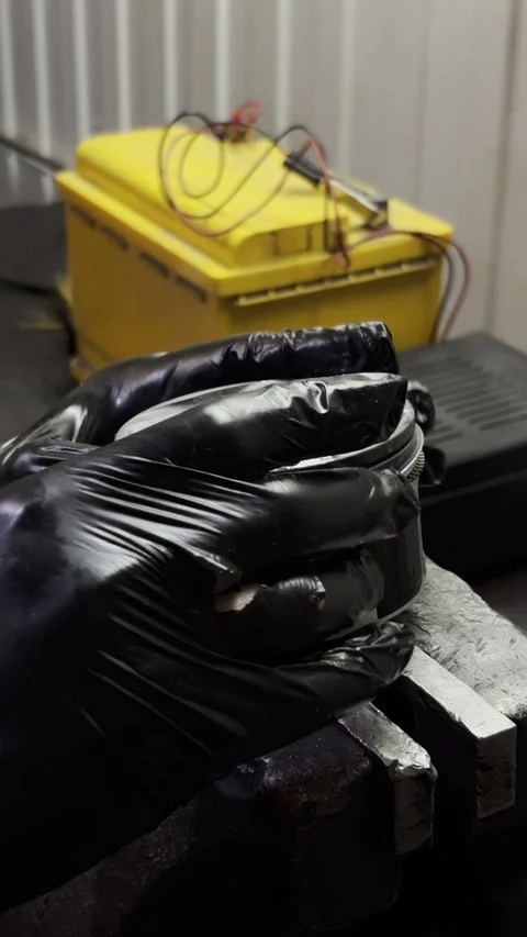 Black gloved hand touching car piston held in metal vise. Stock Footage 332064828
