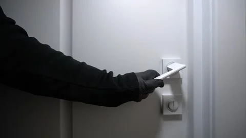 A black-gloved hand turns the white door handle. Stock Footage 320574379