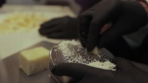 Black gloved hands grating cheese on a pasta grater, pizza grater. Stock Footage 300028376