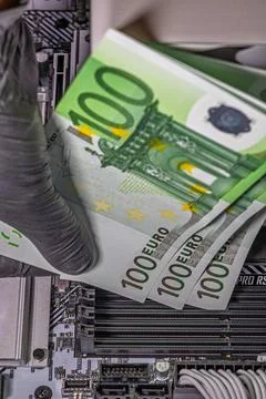 Black-gloved hands inserting 100 euro banknotes into empty RAM slots on a m.. Stockfoto's