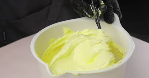 Black-gloved hands of a pastry chef stirring butter or cream in a white bowl Stock Footage 165805729