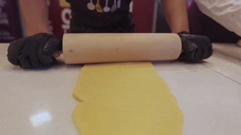 Black gloved hands rolling out pasta dough, pizza dough. Stock Footage 300028345