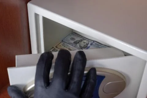 The black-gloved right hand opens the safe deposit box door. Theft of dollars Stock Photos
