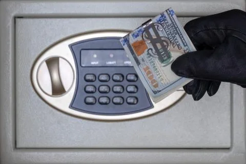 A black-gloved thief opens the safe door with a combination lock. Security at Stock Photos