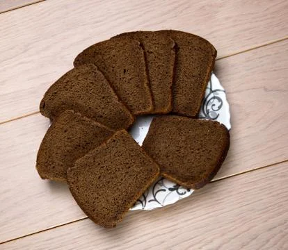 Black grain bread a plate isolated on wooden table background Foto stock