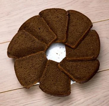 Black grain bread a plate isolated on wooden table background Stock Photos