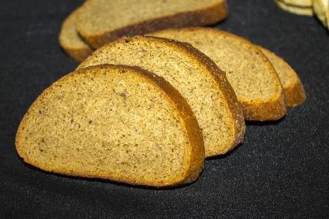 Black grain bread, slice of bread on black background Stock Photos