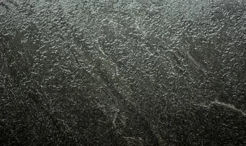 Black granite, natural stone surface close-up with traces of rough processing Stock Photos