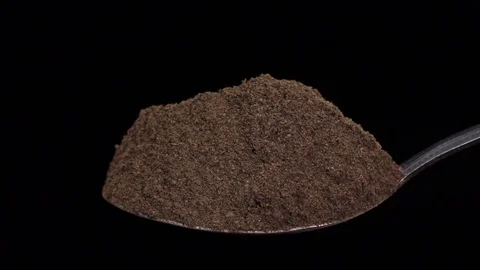 Black ground pepper falling from the iron spoon, black background, slow motion Vidéo 74726482
